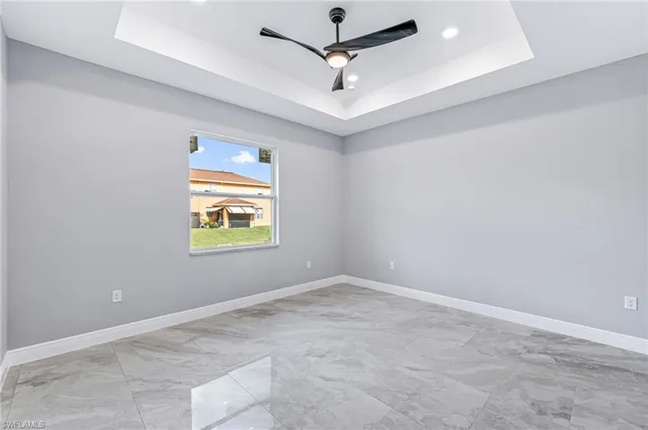 Spare room featuring a tray ceiling and ceiling fan