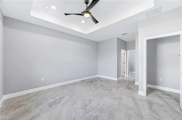 Unfurnished bedroom with a raised ceiling and ceiling fan