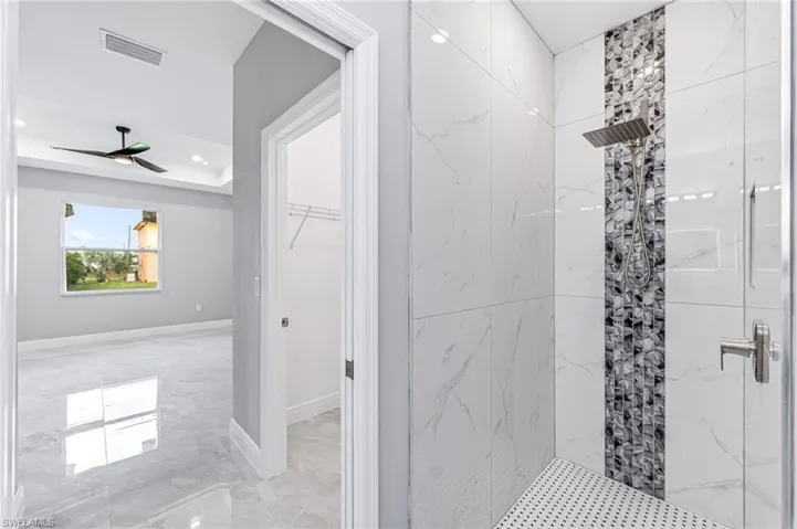 Bathroom featuring tiled shower and ceiling fan