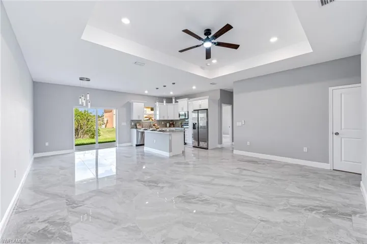 Unfurnished living room with a tray ceiling and ceiling fan