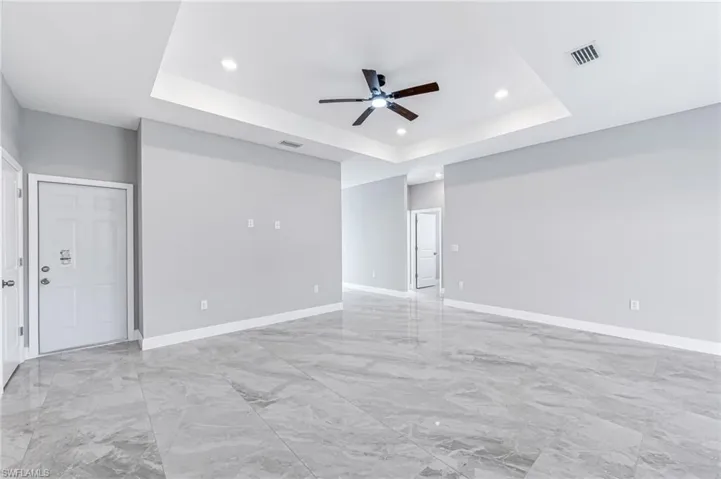 Empty room with ceiling fan and a tray ceiling