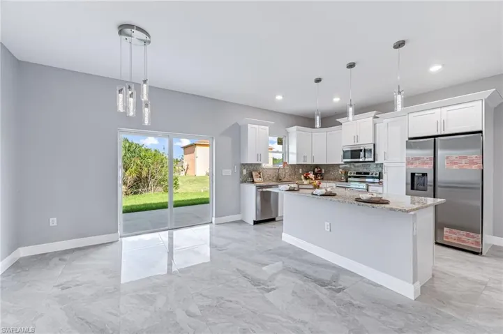 Kitchen featuring white cabinets, hanging light fixtures, a kitchen island, and stainless steel appliances