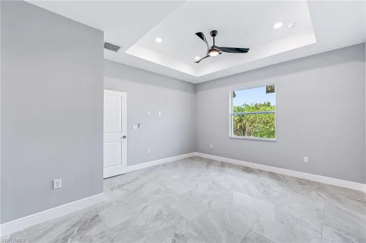 Empty room featuring ceiling fan and a raised ceiling
