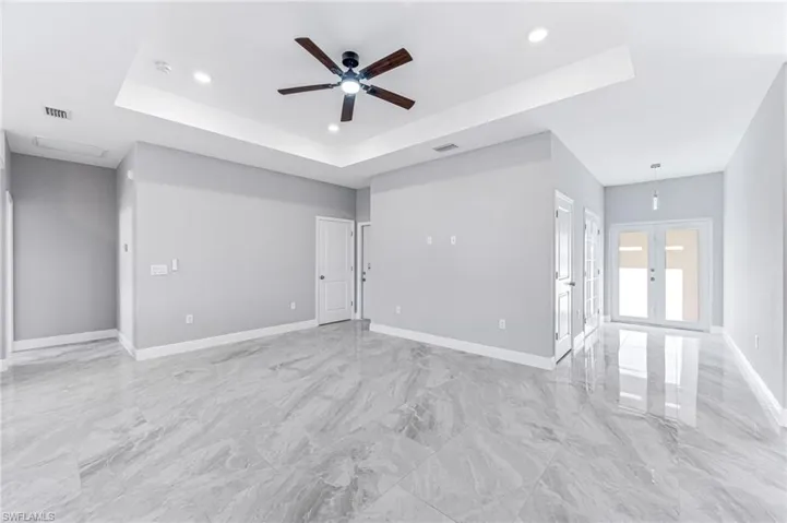 Unfurnished room with ceiling fan, a raised ceiling, and french doors