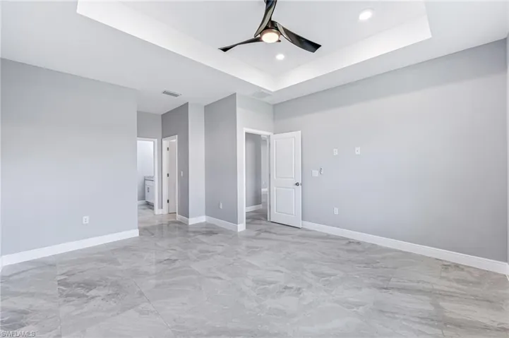 Unfurnished bedroom featuring a tray ceiling and ceiling fan
