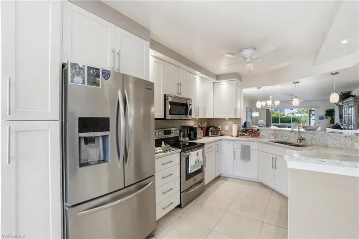 Kitchen featuring stainless steel appliances, white cabinets, light tile patterned floors, and ceiling fan