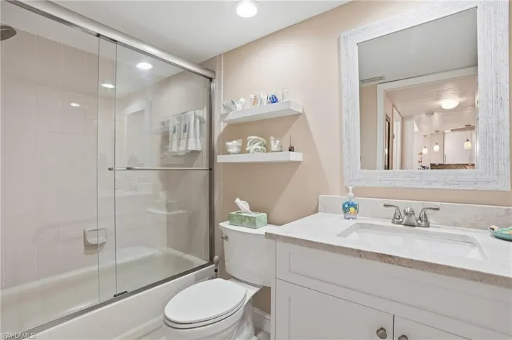 Full bath with vanity, enclosed tub / shower combo, and recessed lighting