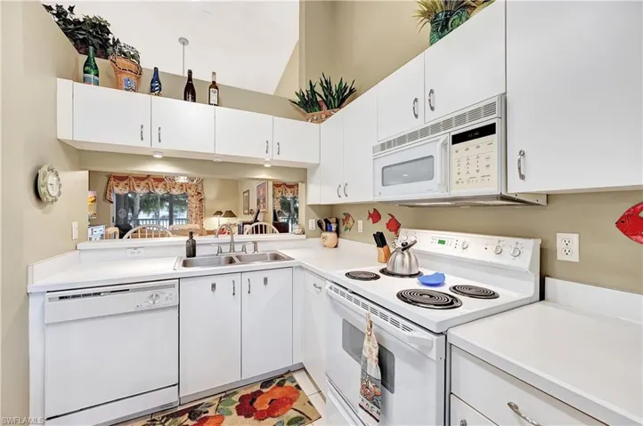 Kitchen featuring white appliances, white cabinetry, and light countertops