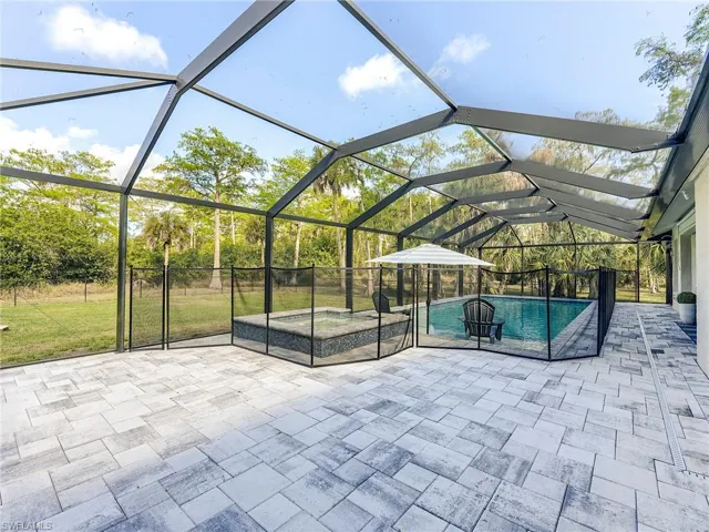 View of patio / terrace with a jacuzzi, an outdoor pool, a sunroom, and a lanai
