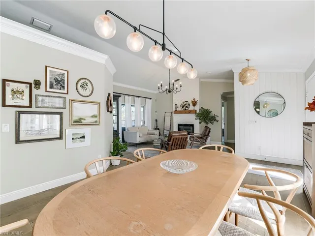 Dining space featuring crown molding, a glass covered fireplace, wood finished floors, and suspended lighting