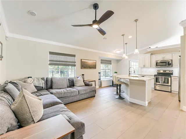 Living room featuring crown molding, ceiling fan, light wood finished floors, and vaulted ceiling