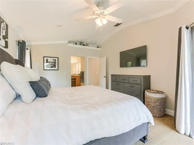 Bedroom featuring vaulted ceiling, crown molding, a ceiling fan, and light wood-style floors
