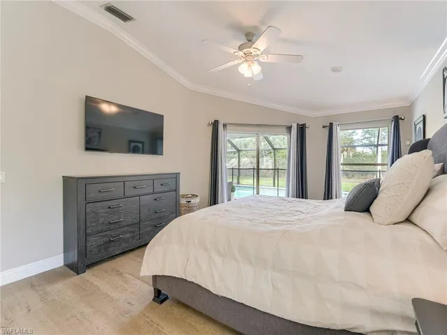 Bedroom featuring ornamental molding, light wood finished floors, access to exterior, multiple windows, and a ceiling fan