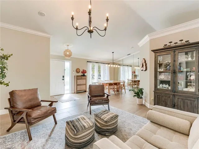 Living area with suspended lighting, crown molding, and light wood-style floors