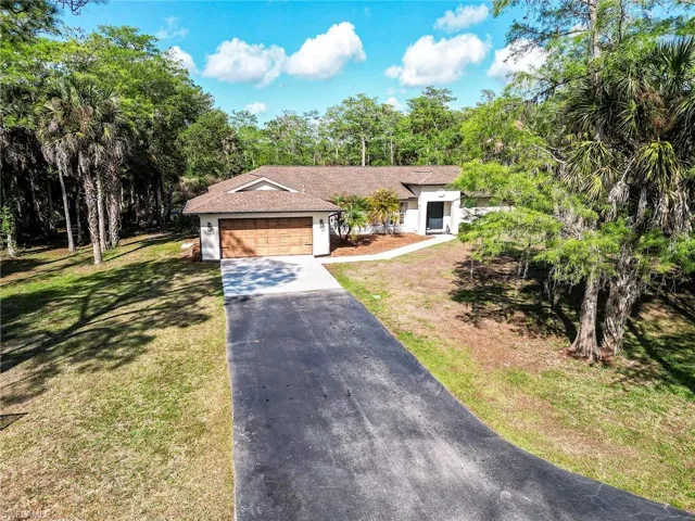 View of front facade featuring driveway, a garage, a front yard, and roof with shingles