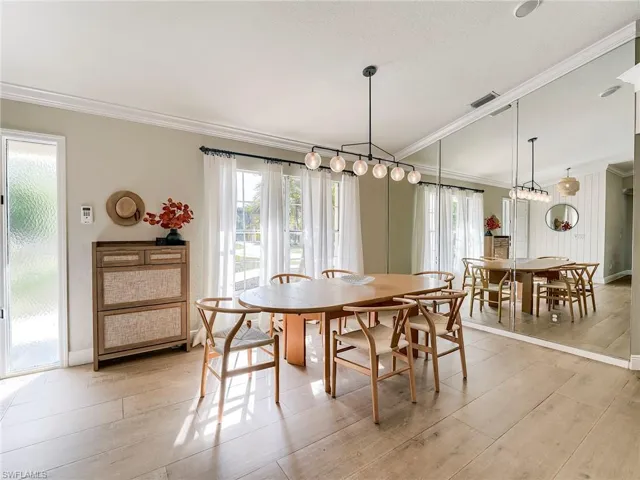 Dining area featuring ornamental molding, light wood-style flooring, and a textured ceiling