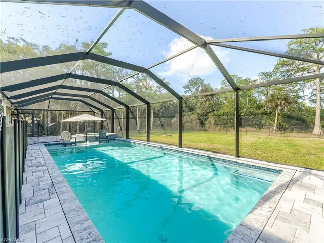 Swimming pool featuring a lanai, a fenced backyard, a sunroom, and a patio