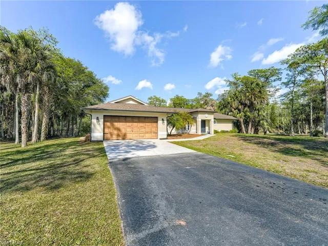 Single story home featuring an attached garage, driveway, a front yard, and stucco siding