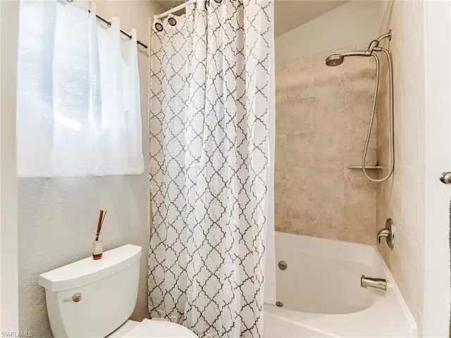 Bathroom with shower / bath combo and a textured wall