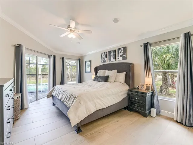 Bedroom with access to exterior, light wood-style floors, multiple windows, and ornamental molding