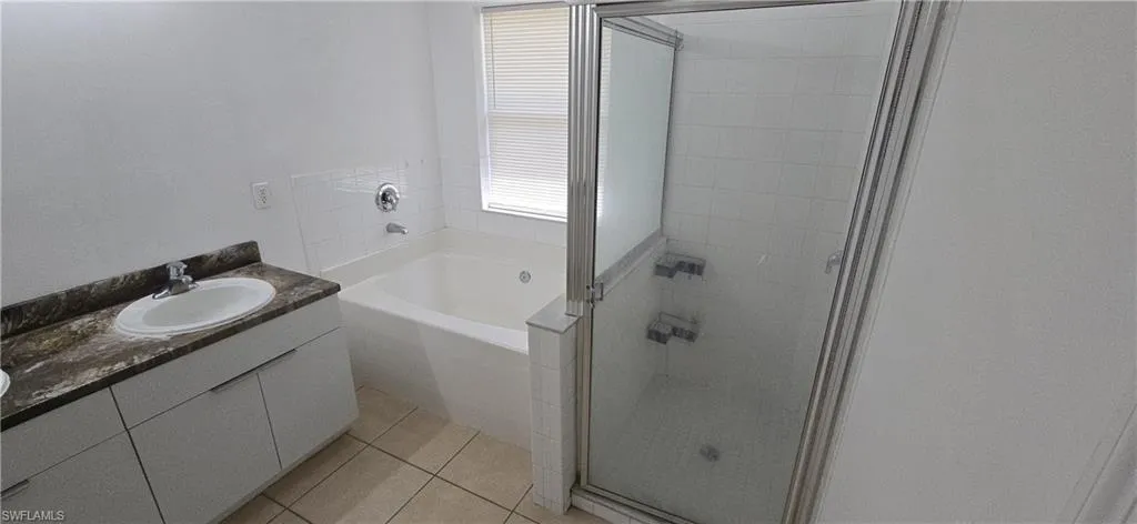 Full bath featuring a stall shower, a garden tub, vanity, and tile patterned floors