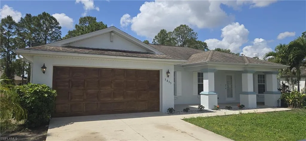 Ranch-style house with an attached garage, concrete driveway, stucco siding, a porch, and a front lawn
