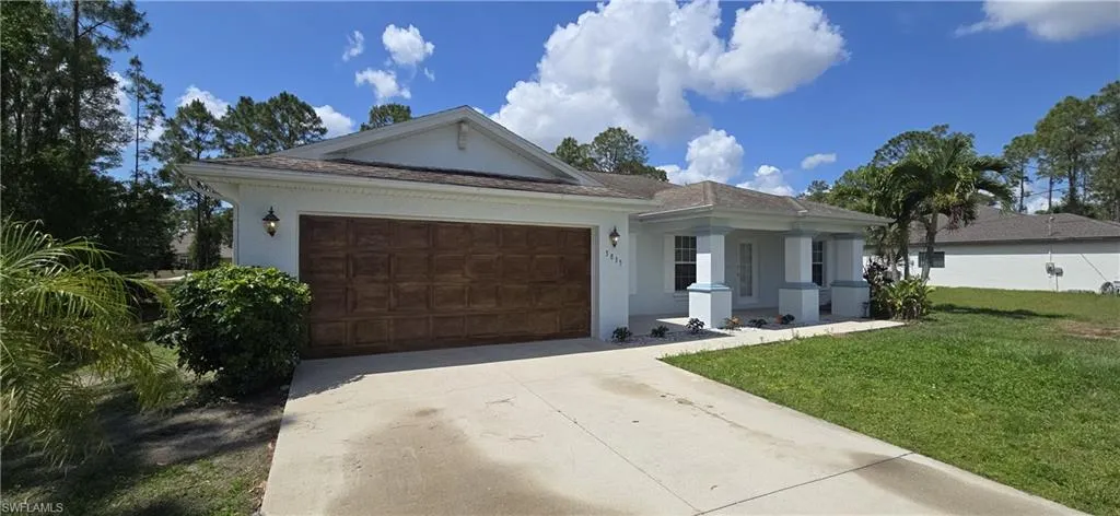 Ranch-style house featuring concrete driveway, a front lawn, stucco siding, a garage, and covered porch