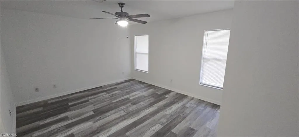 Spare room featuring plenty of natural light, dark wood-style flooring, and a ceiling fan