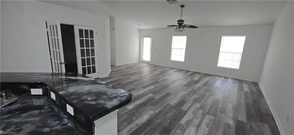 Living area featuring wood finished floors, baseboards, and ceiling fan