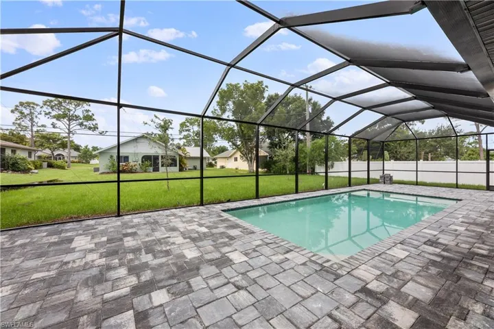 View of swimming pool with a patio, glass enclosure, and a yard