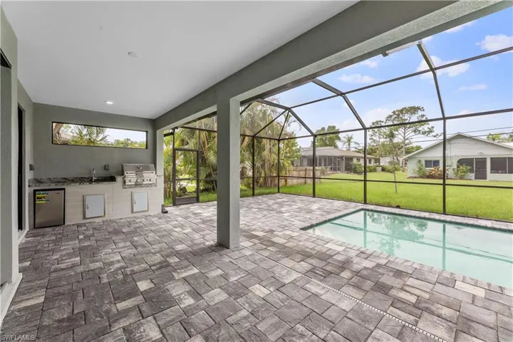 View of pool with a grill, a patio area, area for grilling, a yard, and glass enclosure