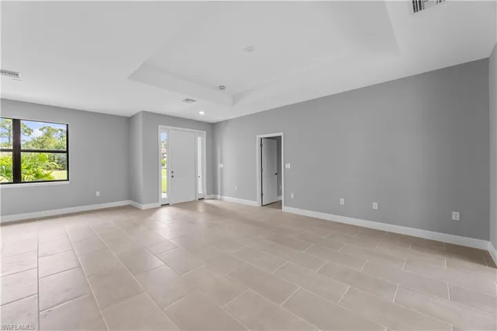 Unfurnished room with a tray ceiling and light tile flooring