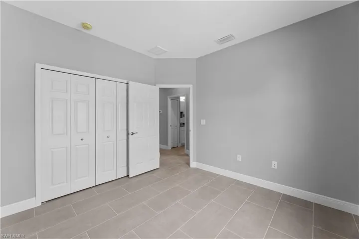 Unfurnished bedroom with a closet and light tile floors