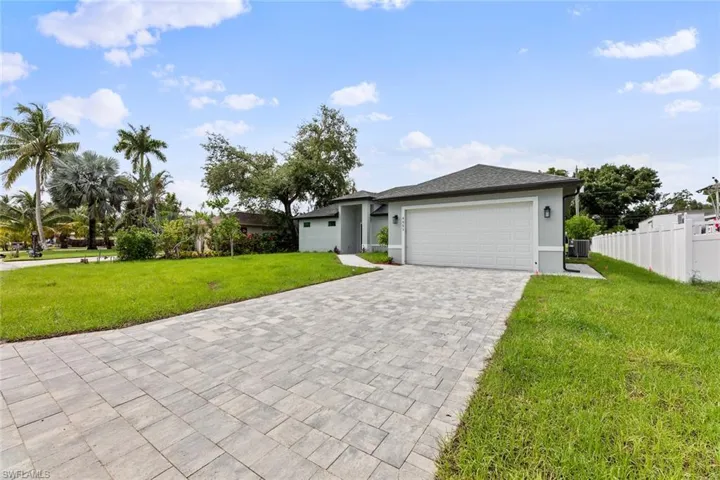 View of front of house with a garage, central AC unit, and a front lawn