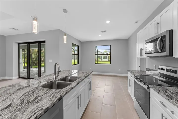Kitchen featuring sink, white cabinets, light tile floors, and stainless steel appliances