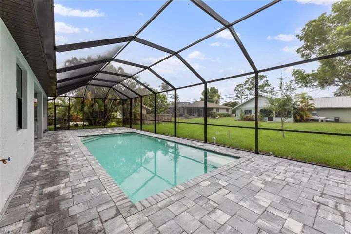 View of swimming pool with a yard, glass enclosure, and a patio area