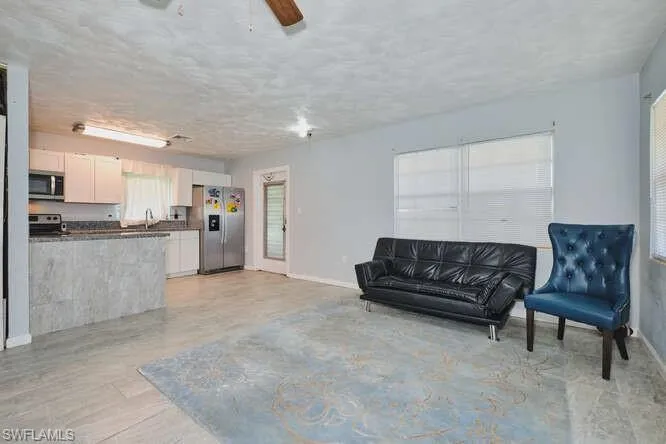 Living room featuring ceiling fan and a textured ceiling