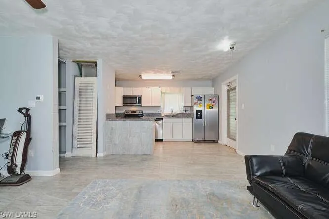 Living room featuring baseboards and a textured ceiling