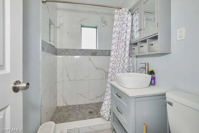 Bathroom featuring a marble finish shower and vanity