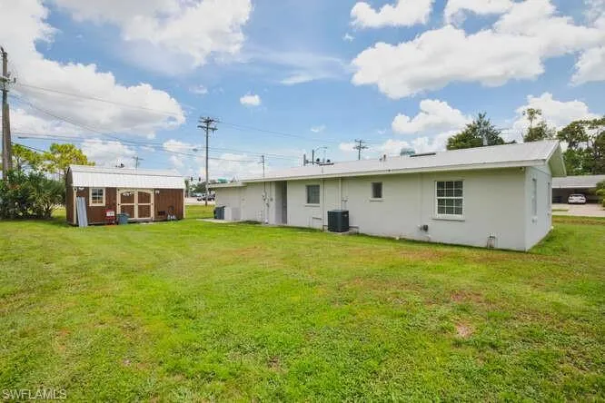 Rear view of property with a yard, stucco siding, and a shed