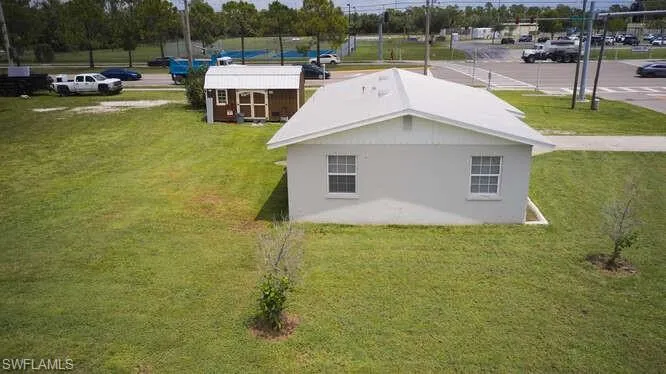 View of side of home with an outdoor structure, a lawn, and stucco siding