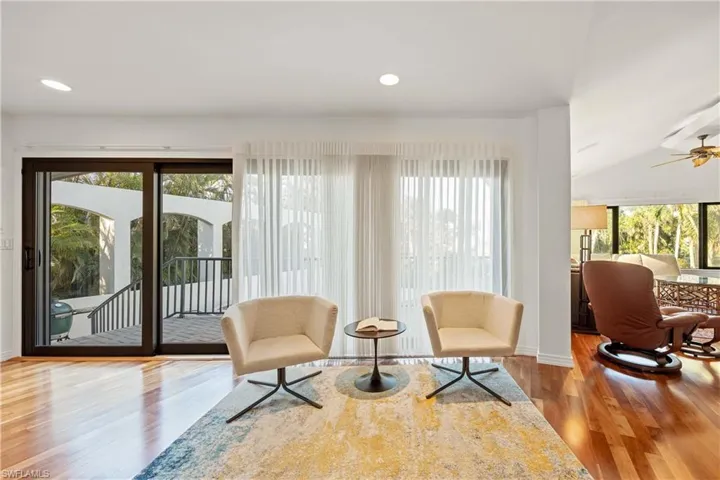 Living area featuring hardwood / wood-style floors, vaulted ceiling, ceiling fan, and a healthy amount of sunlight