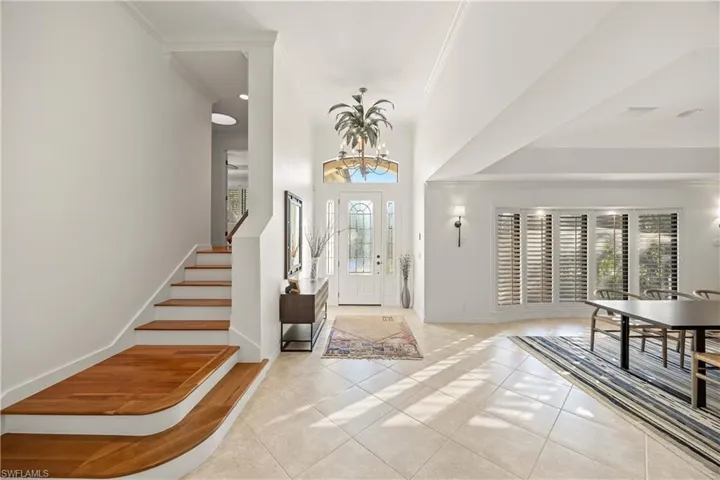 Entryway with light tile patterned floors, ornamental molding, and a chandelier