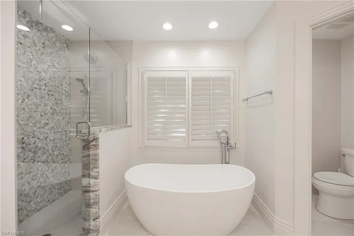 Bathroom featuring toilet, tile patterned flooring, and shower with separate bathtub