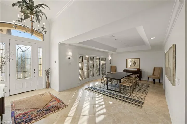 Entryway with a raised ceiling, crown molding, an inviting chandelier, a high ceiling, and light tile patterned flooring