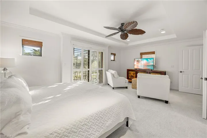 Bedroom featuring ceiling fan, crown molding, a tray ceiling, light carpet, and access to outside