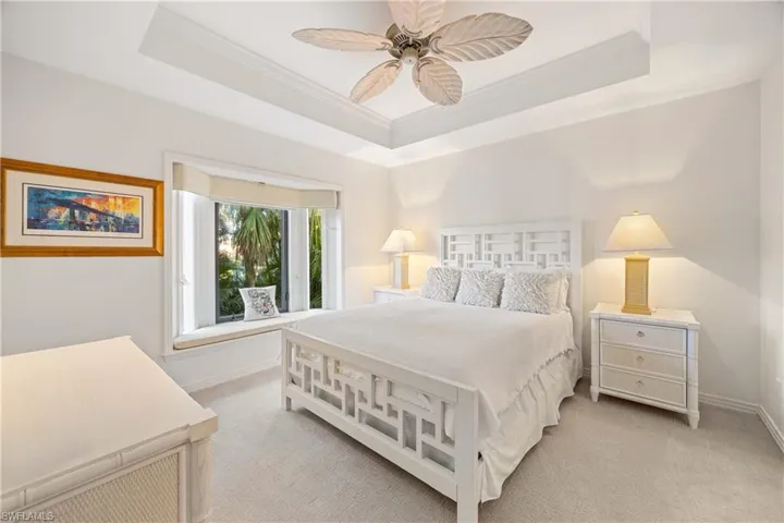Carpeted bedroom featuring a raised ceiling, ceiling fan, and ornamental molding