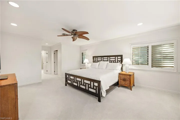 Bedroom with ceiling fan, crown molding, and light carpet