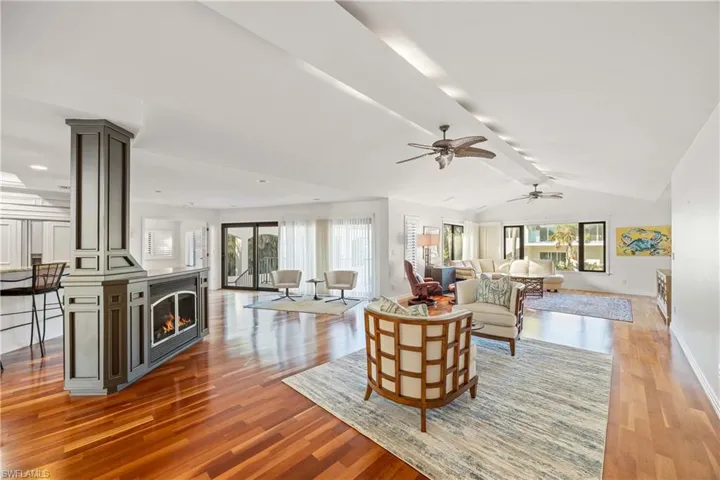 Living room featuring wood-type flooring, vaulted ceiling with beams, and ceiling fan