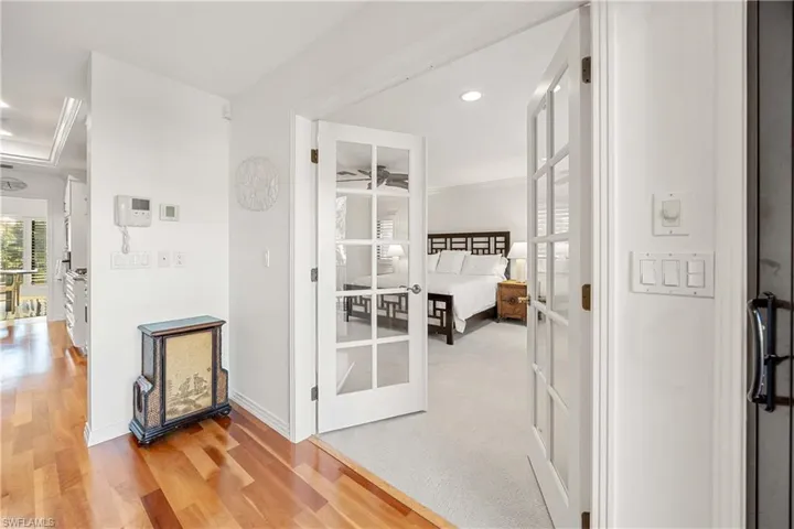 Hall with wood-type flooring, french doors, and ornamental molding